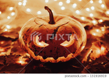 Jack-o-lantern with bright candle light inside. Halloween theme, warm golden colours, pumpkin as a symbol of autumn holiday Jack-o-lantern with bright candle light inside. Halloween theme, warm golden colours, pumpkin as a symbol of autumn holiday 131916919