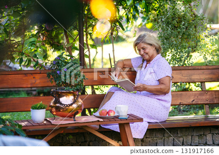 Selfacare moment for elderly woman, quiet reading time in garden. Selfacare moment for elderly woman, quiet reading time in garden. 131917166