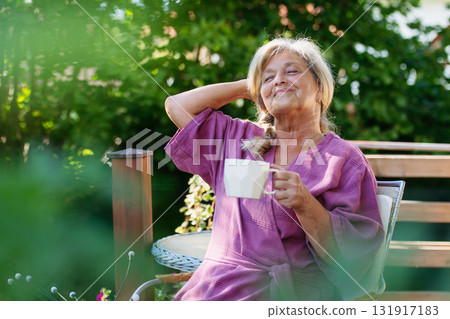 Quiet morning in garden for older woman. Self ritual with coffee. 131917183