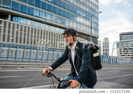 Man riding bike to work in city with helmet and backpack Man riding bike to work in city with helmet and backpack 131917199