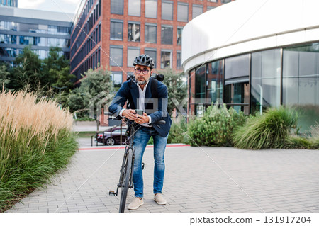 City commuter riding bike from work, reading text message on phone. 131917204