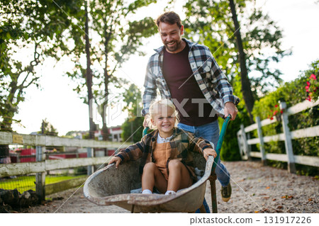 Father pushing toddler boy in wheelbarrow. 131917226
