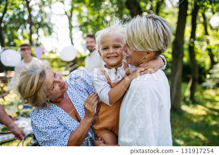 Smiling grandmother talking with her daughter, holding grandchild, family gathering. Smiling grandmother talking with her daughter, holding grandchild, family gathering. 131917254
