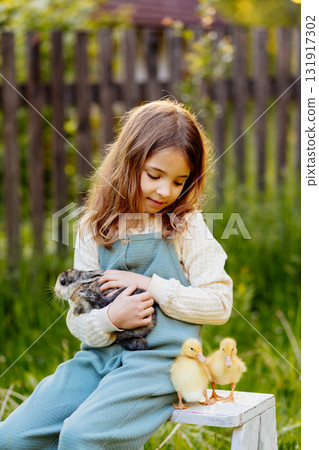 Smiling child playing with baby animals in the garden. Smiling child playing with baby animals in the garden. 131917302