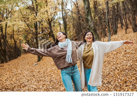 Mature daughter with older mom embracing in autumn park. Mother's day concept. Mature daughter with older mom embracing in autumn park. Mother's day concept. 131917327