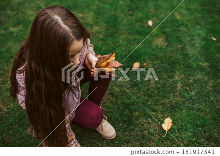 Girl picking fallen autumn leaves in hand, close up. 131917341