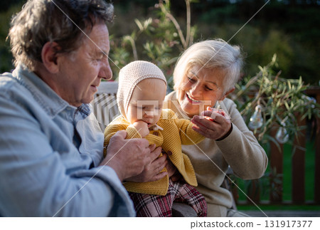 Grandparents holding baby in warm embrace during fall season. Grandparents holding baby in warm embrace during fall season. 131917377