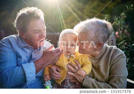 Grandparents holding baby in warm embrace during fall season. 131917378