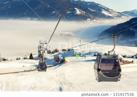 New modern spacious big cabin ski lift gondola against snowcapped forest tree and mountain peaks covered in snow landscape in luxury winter alpine resort. Winter leisure sports, recreation and travel New modern spacious big cabin ski lift gondola against snowcapped forest tree and mountain peaks covered in snow landscape in luxury winter alpine resort. Winter leisure sports, recreation and travel 131917538