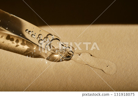 A pipette with cosmetic serum on a beige background. 131918075