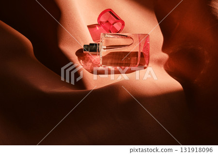 A pink perfume bottle on a soft reddish background. A pink perfume bottle on a soft reddish background. 131918096