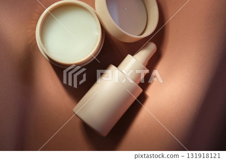 Face cream and serum on a soft beige background. 131918121