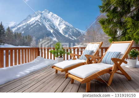 Wooden deck chairs on snowy terrace overlooking mountains 131919150