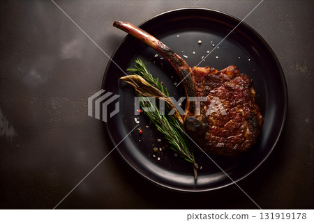 Grilled Tomahawk Steak with Rosemary and Peppercorns on Dark Plate in Rustic Lighting Grilled Tomahawk Steak with Rosemary and Peppercorns on Dark Plate in Rustic Lighting 131919178