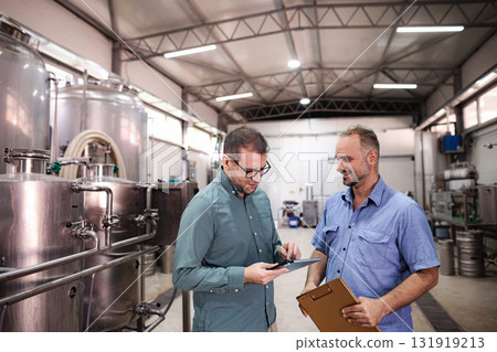 Brewery workers discussing production planning using digital tablet Brewery workers discussing production planning using digital tablet 131919213