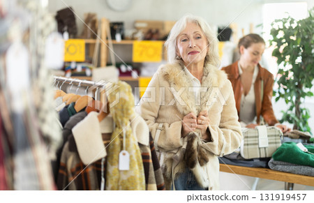 Elderly woman tries on fur coat in clothing store Elderly woman tries on fur coat in clothing store 131919457