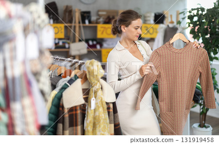 Young woman chooses warm dress in clothing store 131919458