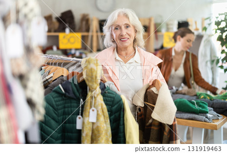 Senior woman customer examine and choose something autumn warm outwear in store Senior woman customer examine and choose something autumn warm outwear in store 131919463
