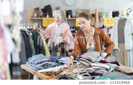 European woman customer choose trousers in store. Other buyer in background 131919468