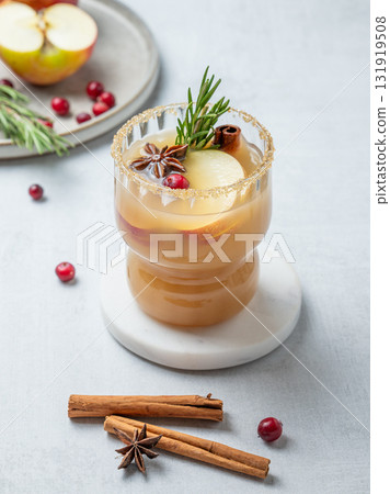 Hot apple cider with cinnamon, anise, brown sugar and rosemary in a glass on a light background Hot apple cider with cinnamon, anise, brown sugar and rosemary in a glass on a light background 131919508