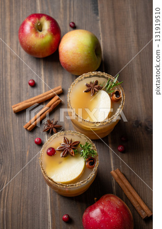 Two glasses of hot apple cider with cinnamon, anise, brown sugar and rosemary on a wooden background Two glasses of hot apple cider with cinnamon, anise, brown sugar and rosemary on a wooden background 131919510