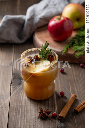 Apple cider with cinnamon, anise, brown sugar and rosemary in a glass on a darb wooden background 131919511
