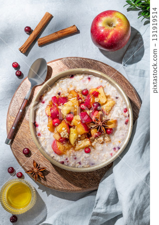 Overnight oatmeal with apples, cranberries, and cinnamon in a bowl on a wooden board 131919514