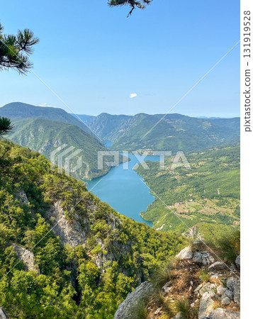 Canyon river meandering among green forested mountains; nature landscape photography under clear sky 131919528