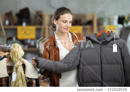 Young woman chooses sweater in clothing store Young woman chooses sweater in clothing store 131919539