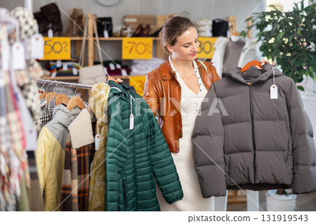Woman choosing a down jacket in a clothing store 131919543