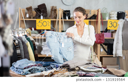 Young woman choosing jeans in clothing store Young woman choosing jeans in clothing store 131919564