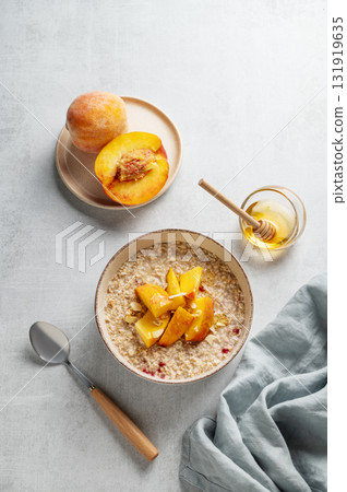 Oatmeal with peaches and nuts in a bowl on a light background with honey Oatmeal with peaches and nuts in a bowl on a light background with honey 131919635
