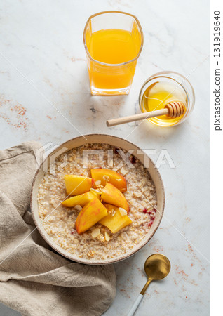 Oatmeal with peaches and nuts in a bowl on a marble background with honey Oatmeal with peaches and nuts in a bowl on a marble background with honey 131919640