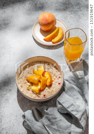 Oatmeal with peaches and nuts  in a bowl on a gray background with honey 131919647