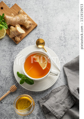 Tea with lemon, ginger, honey, and mint in a cup on a gray background with citrus fruits 131919653
