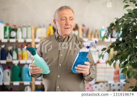 Senior man studies label and choose kitchen cleaner spray 131919674