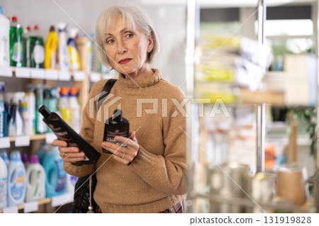 Mature woman chooses products for glass-ceramics 131919828