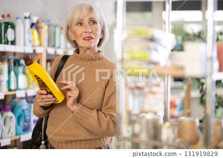 Positive mature woman choosing parquet and wood cleaner in department store 131919829