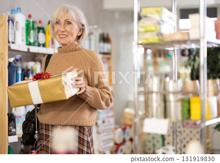 Elderly European woman with gift box in store 131919830