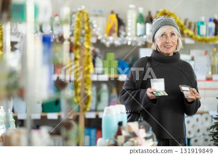 Elderly woman chooses cosmetics in decorated household chemicals store Elderly woman chooses cosmetics in decorated household chemicals store 131919849