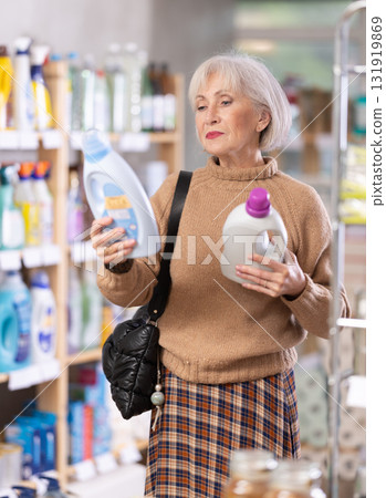 Mature positive woman consumer with household chemical products for washing indoors 131919869