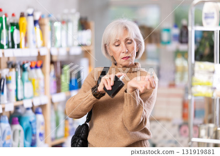 Elderly housewife chooses perfume or aromatic incense in supermarket 131919881