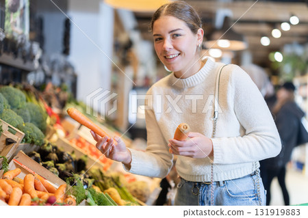 Young woman choosing carrots in grocery supermarket Young woman choosing carrots in grocery supermarket 131919883
