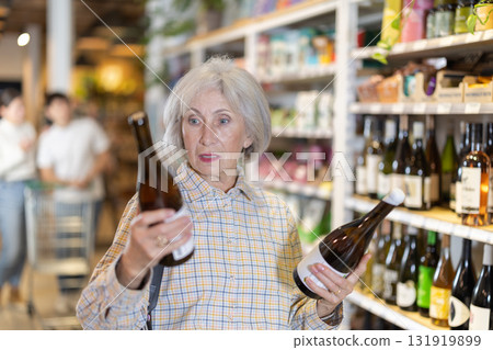 Mature woman choosing wine in store 131919899