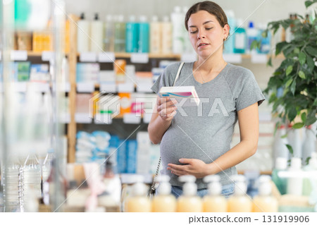 Pregnant woman choosing pills in pharmacy 131919906