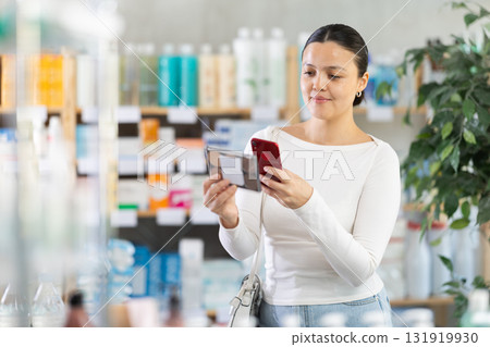 Asian woman scans on mobile makeup packaging 131919930
