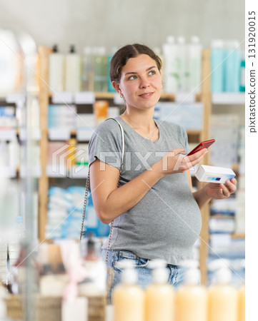 Pregnant woman scanning barcode of ointment at pharmacy Pregnant woman scanning barcode of ointment at pharmacy 131920015