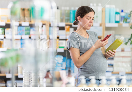 Pregnant woman scanning shampoo in pharmacy Pregnant woman scanning shampoo in pharmacy 131920084