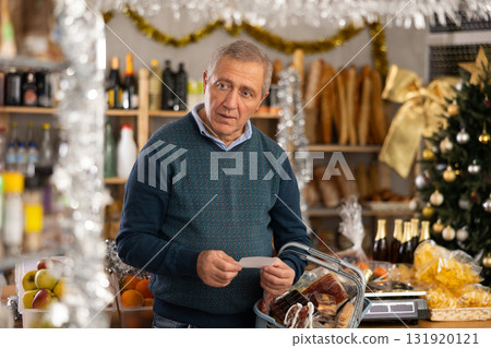 Elderly man buying groceries from shopping list in store Elderly man buying groceries from shopping list in store 131920121