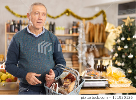 Elderly man with basket of groceries in store 131920126